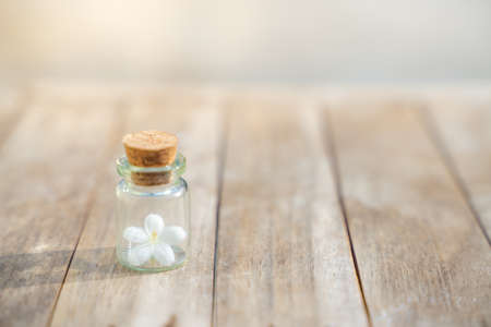 Glass bottles have small flowers on the wooden floor.の写真素材