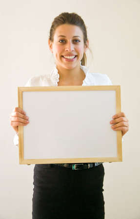 Business woman holding blanco sign at office looking into the lensの写真素材