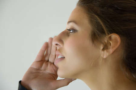 woman having a private conversation by holding her hand to her mouth. She could also be ready to shout.の写真素材