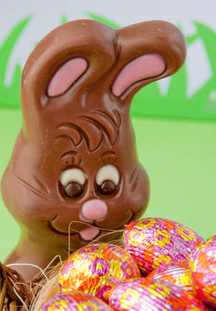 Chocolate Easter bunny behind a basket of decorated eggs
