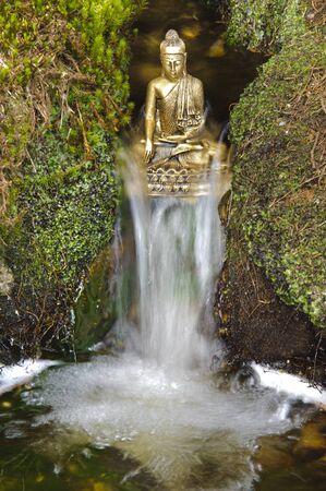 chinese buddha sculpture sitting in flowing water cascadeの写真素材