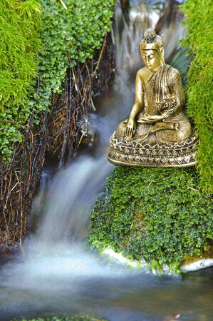 Buddha figure is sitting over water cascadeの写真素材