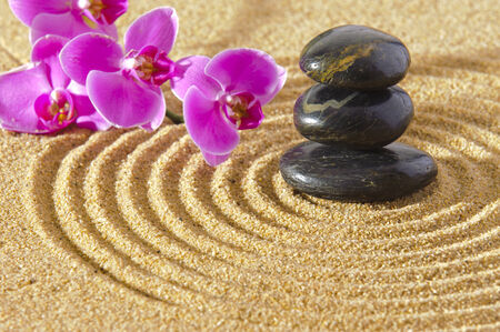 Japanese ZEN garden in sand with stacked stones and orchid flowerの写真素材