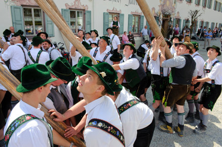 In many villages of Bavaria it is an historical customs to erect a high and decorated tree at 1. May by local men and with muscle power, clothed in traditional bavarian dress with short leather trousers and white shirts. After erecting the tree, men and wのeditorial素材