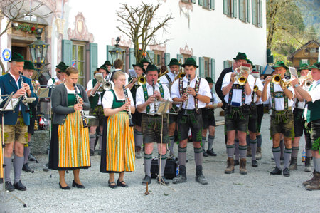In many villages of Bavaria it is historical customs to erect an decorated high tree at 1. May by local men, clothed in traditional bavarian dress with short leather trousers and white shirt. While other local men are working to put up the tree, a Bavariaのeditorial素材