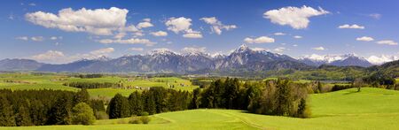 panoramic landscape with meadow and lake in front of alps mountainsの写真素材