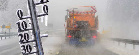 Road sign and thermometer with sub-zero temperatures warn of snow, ice and slipperiness