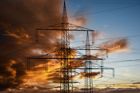 high voltage electric pylons against sky with dramatic cloudsの写真素材