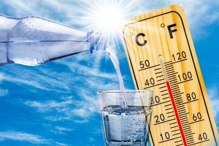 thermometer shows high temperature in summer heat and bottle with water with drinking glassの写真素材