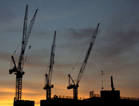 Cranes on top of a new building development at sunset.