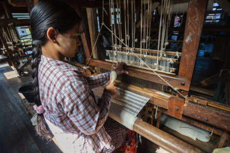 The local worker is weaving with handloom in the factory center of famous lake on December 26, 2013 in Inle, Myanmar.のeditorial素材