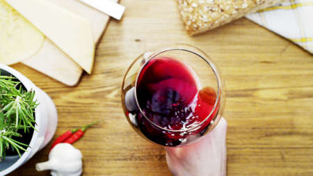 Red Wine Moving Up in a Glass Holded by a Manの写真素材