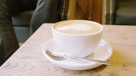 Cup of Coffee and a Teaspoon. Man Sitting Nearby
