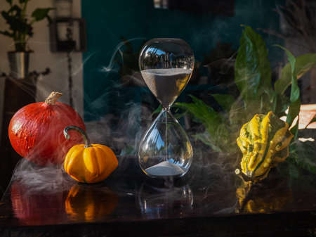 Halloween time countdown modern hourglass against a blurry background from the window - sand seeping...