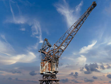 France, Caen, January 25, 2020. Old gantry crane standing at the canal wharf in the harbor used for unloading. Blue sky at sunset. Beautiful photo to picture on the wall.のeditorial素材