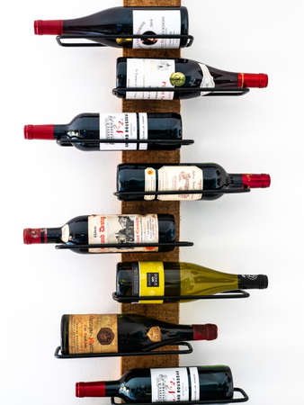 Caen, France, March 2021: A bottle of different wines on the wall in a special metal stand, Wine...