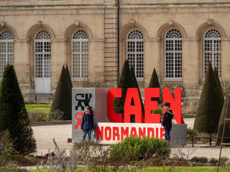 Caen, France, February 2021. Saint Etienne Church, Caen, France. A stand with the inscription -Caen Normandy. A boy and a girl standing next to the childrenのeditorial素材