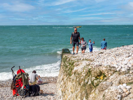 Etretat, France, Normandy, September 2021. People, tourists walking on the pebble beach, in the background the ocean and blue skyのeditorial素材