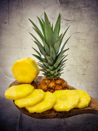 Juicy pineapple fruit sliced on a wooden board, healthy food for vegetarian, marble stone backgroundの写真素材