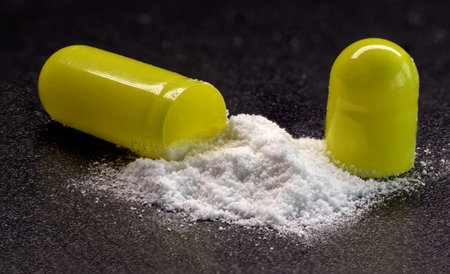 capsules tablets - open white powder sprinkled on black background, macro photoの写真素材