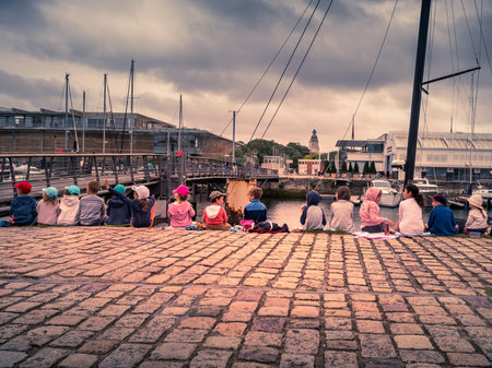 La rochelle, France, July 2022. A young, blonde woman is walking on the beach with a sailing ship and a lighthouse in the background. Relax, vacationのeditorial素材