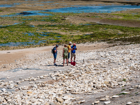 La rochelle, France, July 2022. A young, blonde woman is walking on the beach with a sailing ship and a lighthouse in the background. Relax, vacationのeditorial素材