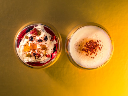 Cappuccino coffee and dessert with jelly with cream with raisins in chocolate - top view golden backgroundの写真素材