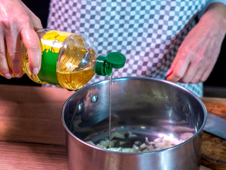 rapeseed oil is best for healthy frying at high temperature, pouring oil into a pot, bottle of rapeseed oil in a woman's hand, pouring oilの写真素材
