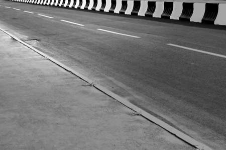 Asphalt road with a fence black and white colorの写真素材