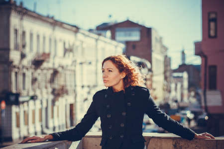 Portrait of red-haired girl on the background of the city