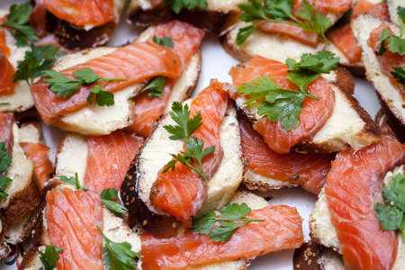 A heap of sandwiches with red fish meat and green parsleyの写真素材