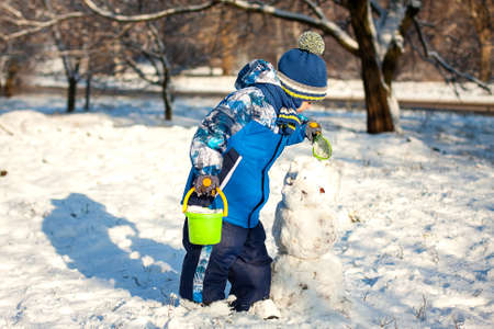 Little boy makes a snowman in the streetの写真素材