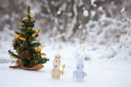 couple of snowmen in the winter woods near a Christmas treeの写真素材