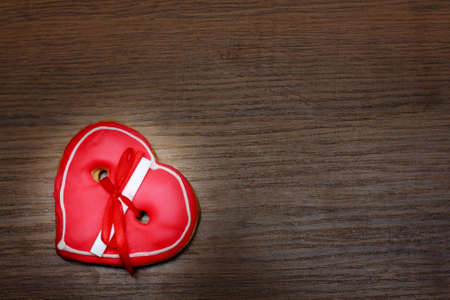 heart shaped cookie with red ribbon on a wooden backgroundの写真素材