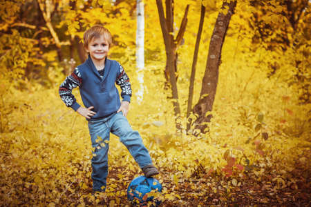 smiling boy in autumn forest with a soccer ballの写真素材