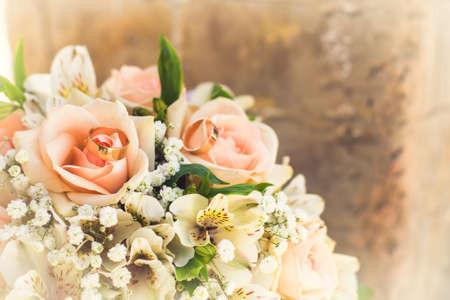 golden rings on wedding bridal bouquet with white, peach and orange roses. Wedding themeの写真素材