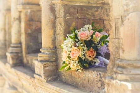 wedding bridal bouquet with white, peach and orange roses lies in the ancient building. Wedding themeの写真素材