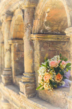 wedding bridal bouquet with white, peach and orange roses lies in the ancient building. Wedding themeの写真素材