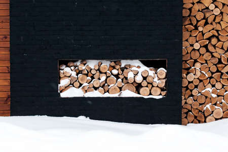 Cutting firewood stacked outside in the snow
