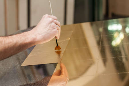 Master works with a thin gold leaf pieces on glass hands in the center of the frameの写真素材