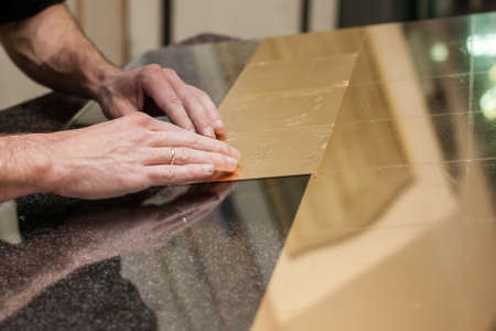 Master works with a thin gold leaf pieces on glass hands in the center of the frameの写真素材