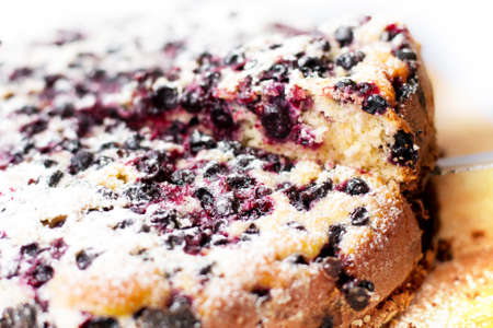 home-made cake with blueberries and powdered sugar on wooden tableの写真素材