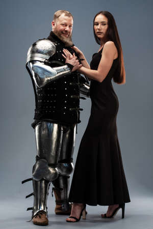 Beautiful girl in a black dress next to a knight in armorの写真素材