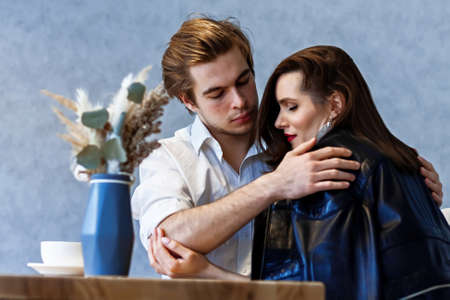 beautiful couple in a cafe at a table drinks coffee and talking about somethingの写真素材