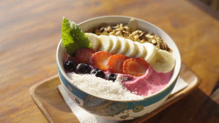 A delicious bright tropical bowl with smoothie, granola, dragonfruit, sliced bananas, mint,...