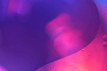 Abstract shapes of pink water forming a wave like a sine-curve in front of a blue blurred backgroundの写真素材