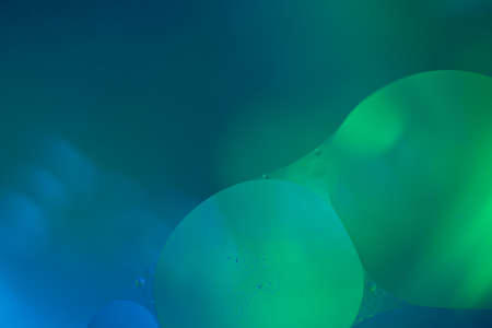 Abstract two big bubbles of water forming a union in front of a blurred background