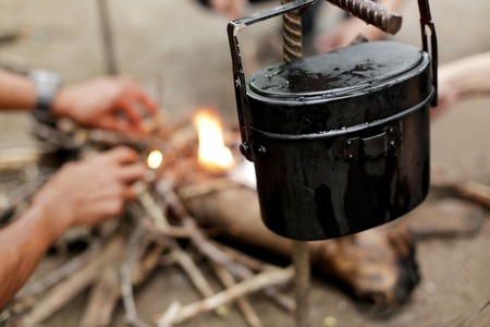 Cooking food on the campfire in the forest. The small pots on fire at camping place. Selective...