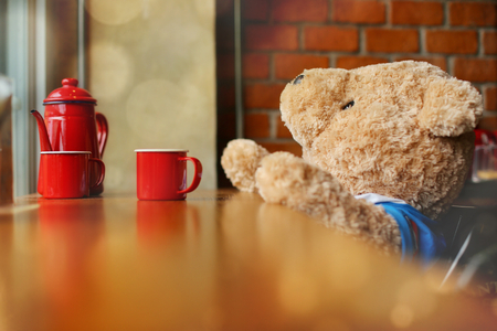 Doll bear and coffee set on wooden bar. Relax time concept, selective focus and toned image.の写真素材