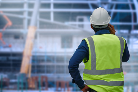 The engineer standing orders for construction crews to work on blurred site background. Industry and...
